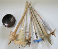A selection of supported spindles, drop spindles, and a spindle bowl.